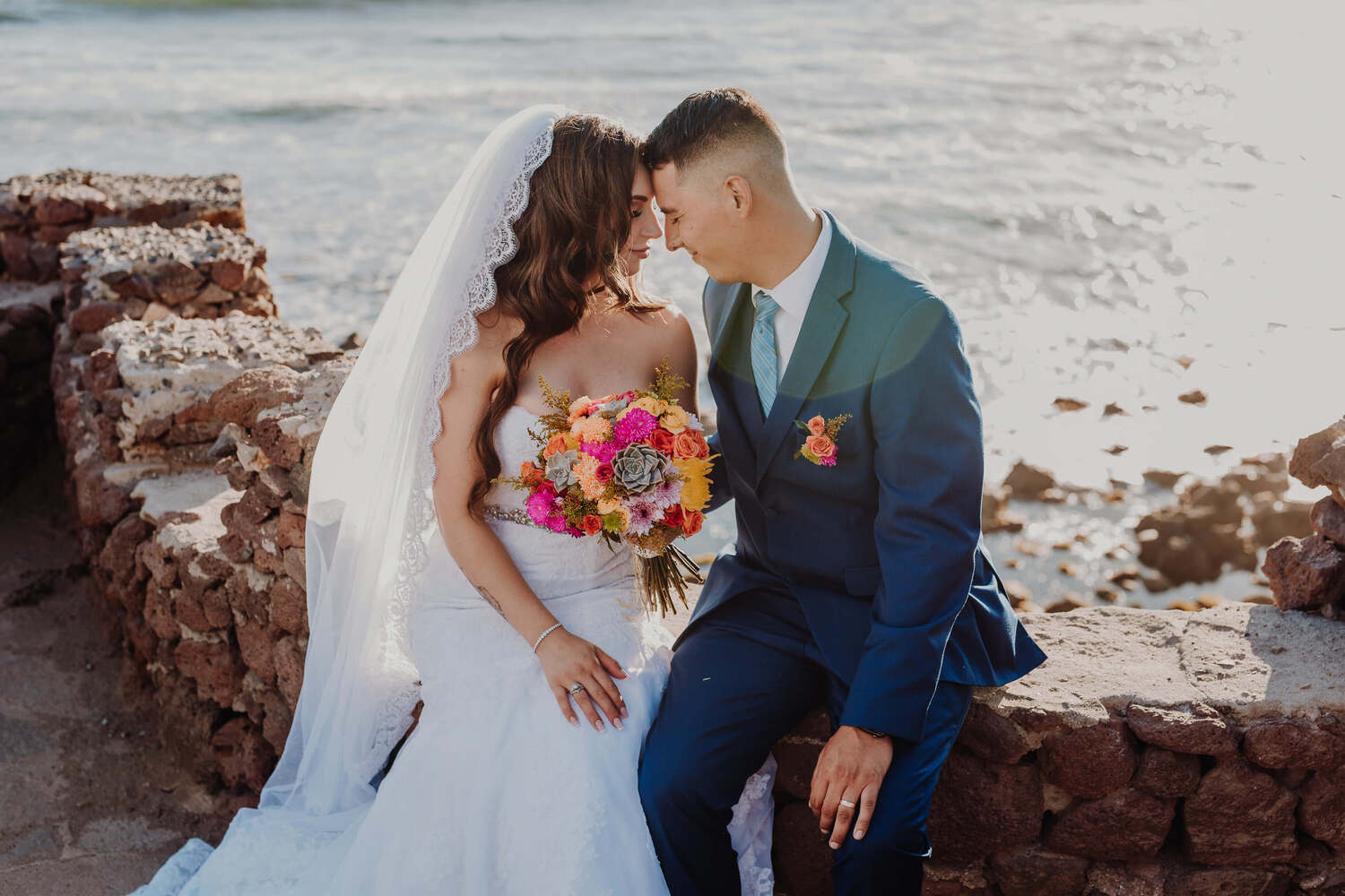 A couple posing very close in front of ocean at the wedding