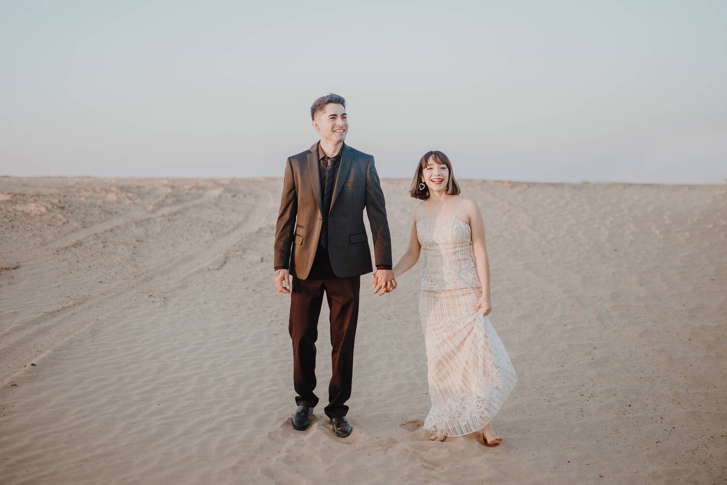 A couple holding hands in the desert after the wedding